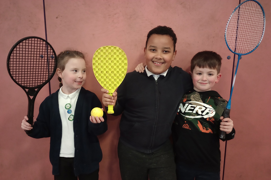 Three children holding different types of racquet