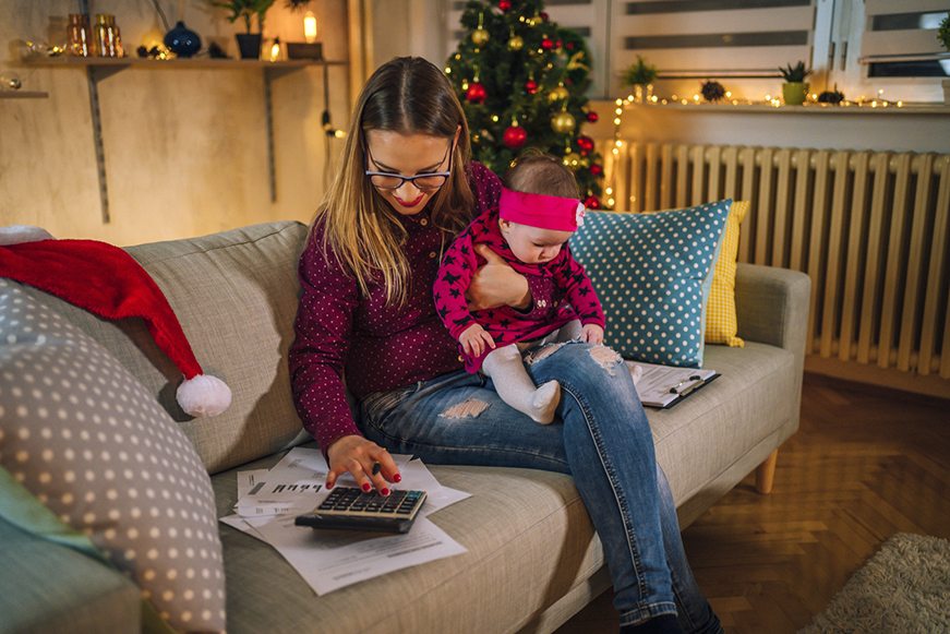 Woman and child sitting on a sofa, using a calculator, in a room with Christmas decorations