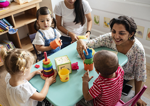 A child carer with young children in a nursery