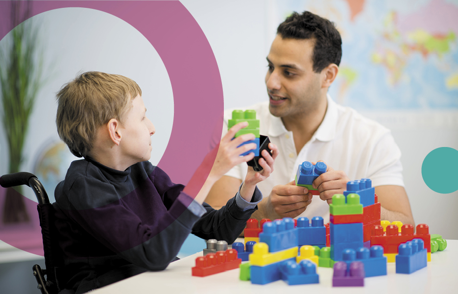 Social worker and disabled boy playing with toy bricks