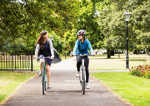 Two cyclists side-by-side on a park path