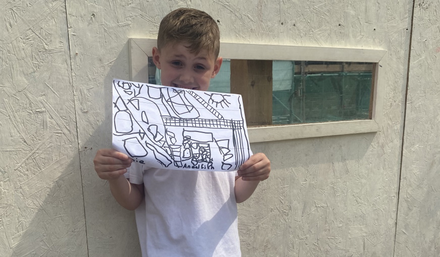Boy from Newlands Primary School holding drawing in front of window