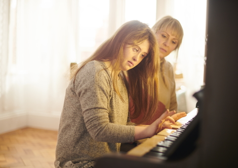 Young woman with Down's syndrome at piano with teacher