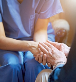 A health care worker holding the hands of another person