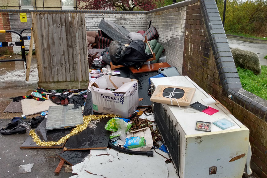 Fly tipped rubbish including boxes, a fridge, and bits of furniture
