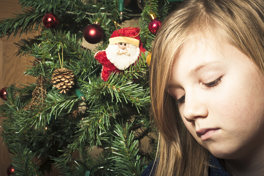 Young Girl Looking Sad Next To Christmas Tree 871X581