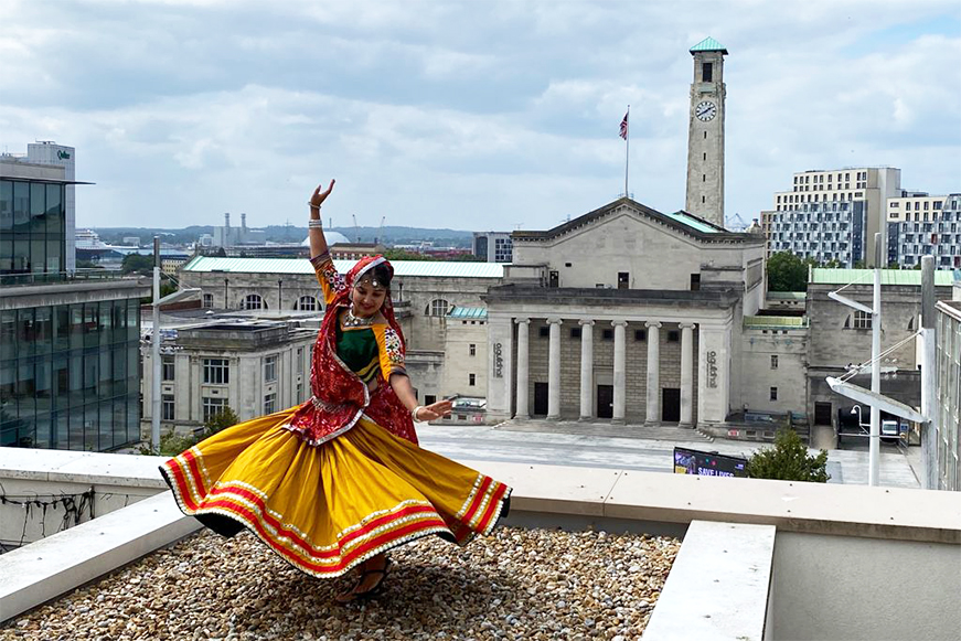 A colourful dancer twirling her skirt on top of a building with Southampton Civic Centre in the background