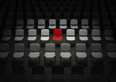 A red chair surrounded by grey chairs