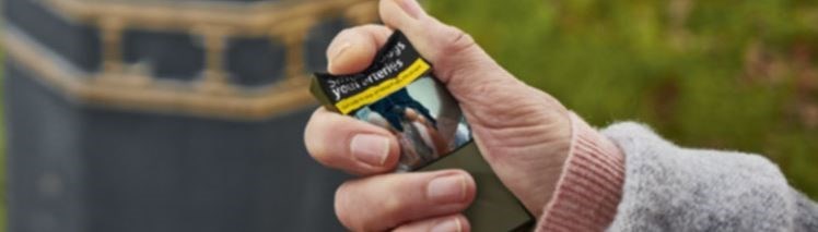 Hand crumpling a cigarette packet
