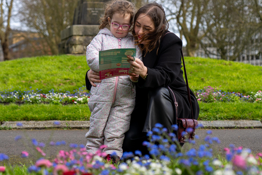 Mum And Child Looking At Easter Trail Map In Park