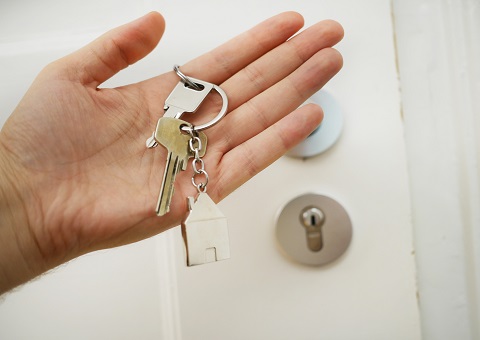 Hands holding keys with a house-shaped keyring