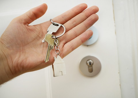 A hand holding keys in front of a door