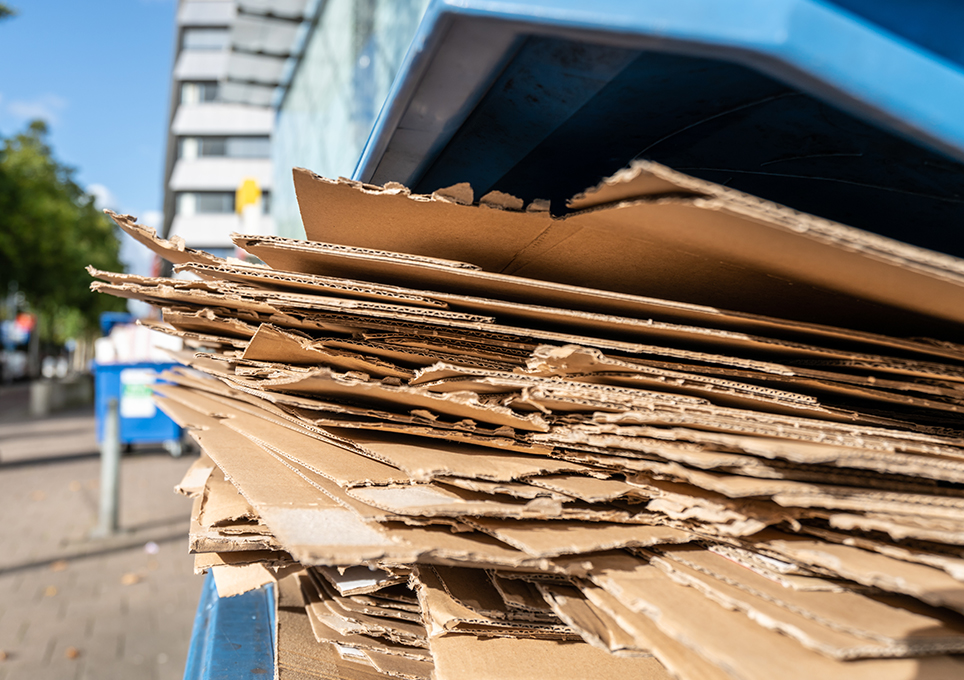 A bin overfilled with cardboard