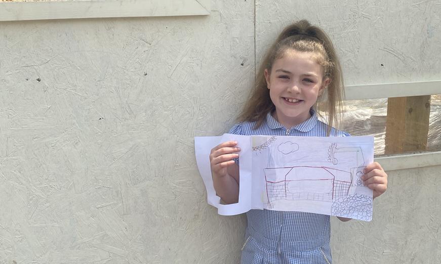 Girl from Newlands Primary School holding drawing in front of window
