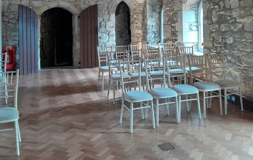Some chairs arranged in rows in a room with wooden flooring and bare stone walls
