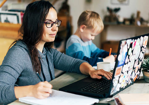 Parent on a laptop with child next to them