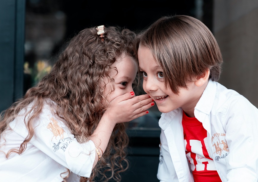 Two children whispering to each other