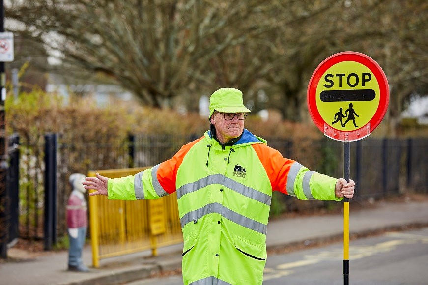 Male school crossing patrol officer with lollipop sign
