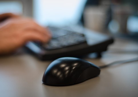 Computer mouse with someone at a keyboard behind