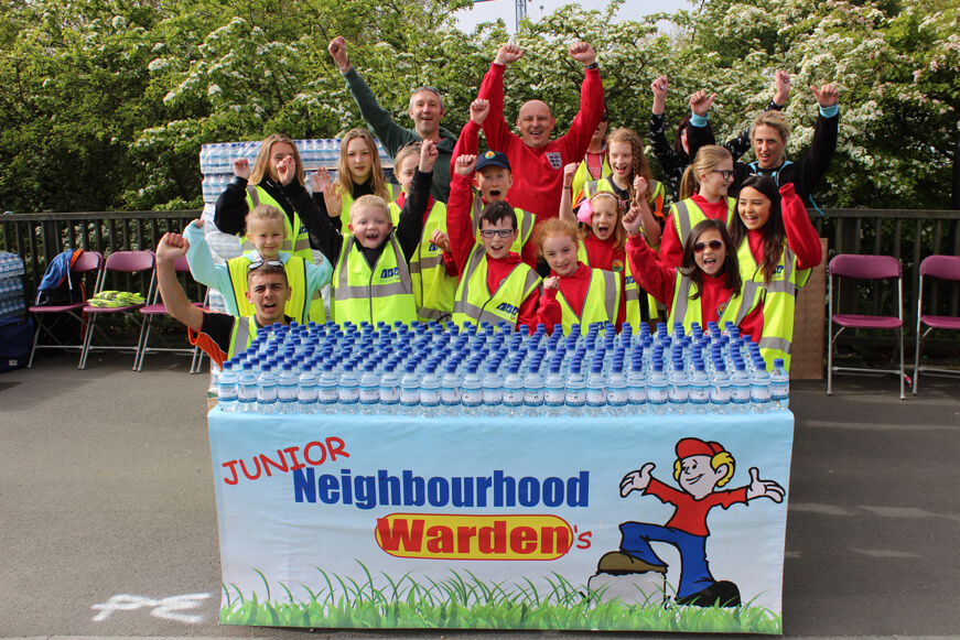 The Junior Neighbourhood Wardens with a water stall at an event. They are cheering