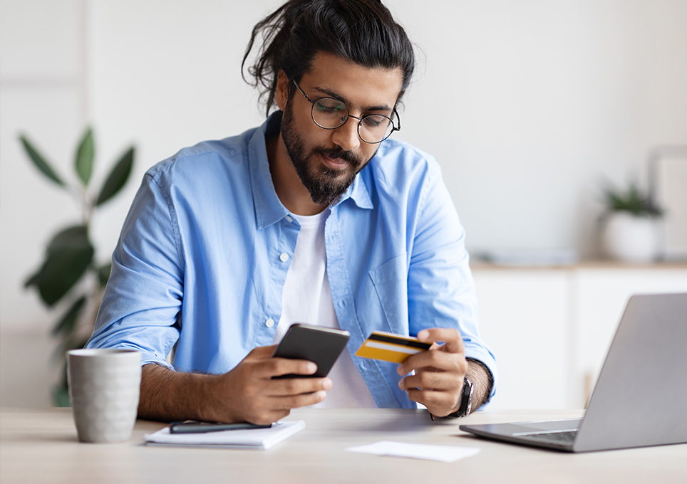 Someone making a payment with a card, their phone and a laptop computer