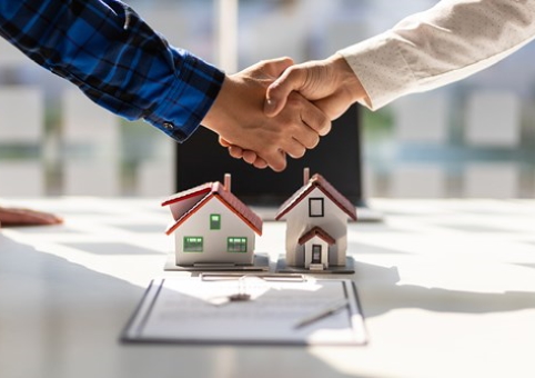 Handshake over a document and two model houses