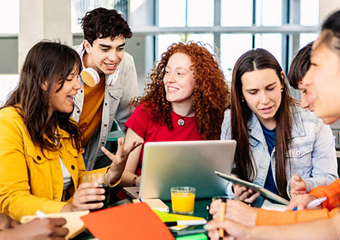 A group of young adults around a laptop