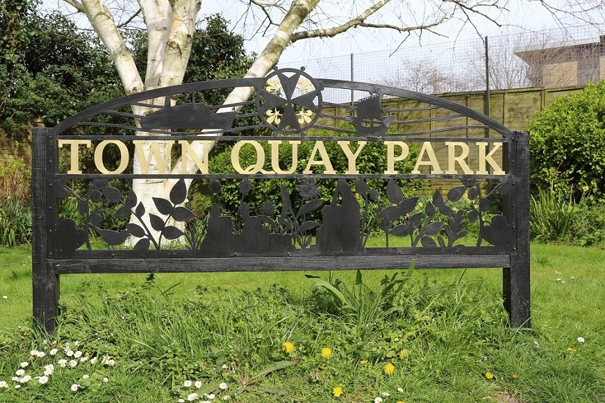 Black decorative sign with gold writing that says 'Town Quay Park'
