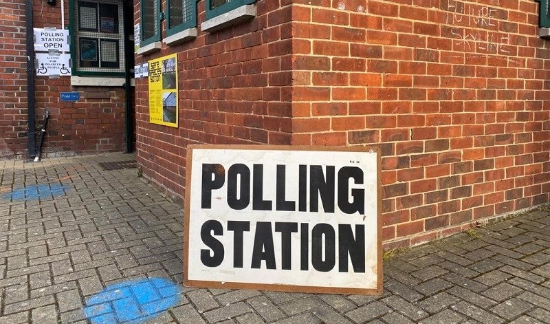 Polling station sign leaning against a wall