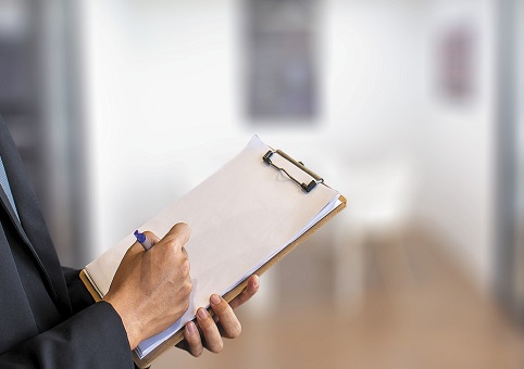 Person writing on a clipboard