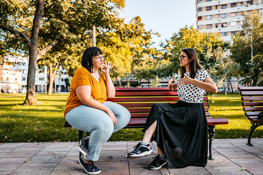 Two People Talking On A Park Bench
