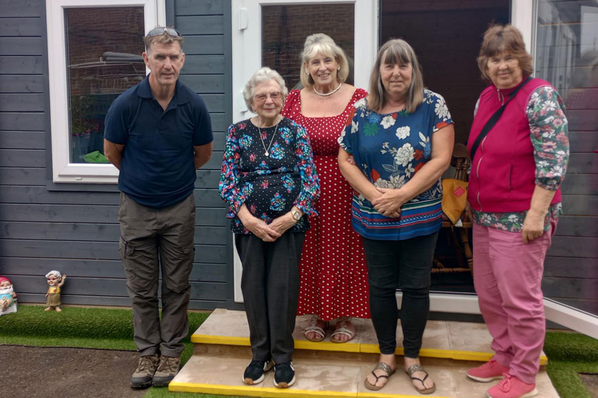 Five people standing together in front of a community hub Five people standing together in front of a community hub