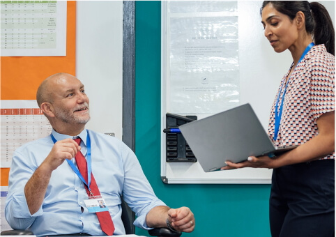 Woman with laptop and man talking in office