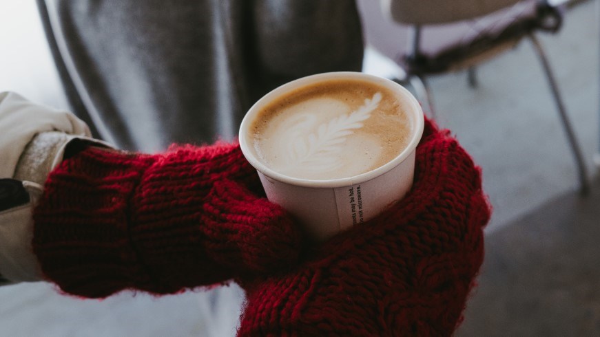 Person wearing gloves holding coffee