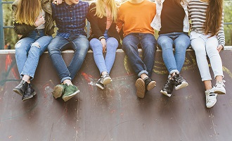 Children and teenagers sitting on a skate ramp