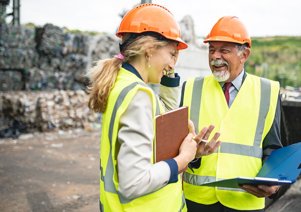 Two people in hard hats and high visibility clothing having a discussion