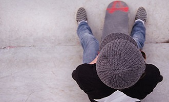Teenage boy sitting on skateboard