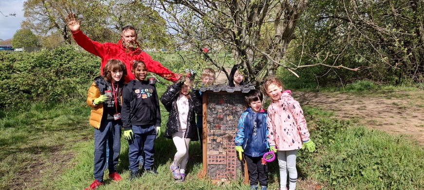 An adult and several children posing with the bug hotels