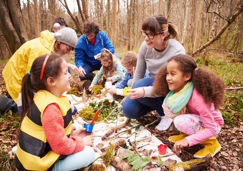 A group of children and adults in a forest 