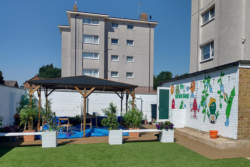 A gardening area with several plants, seats and a gazebo