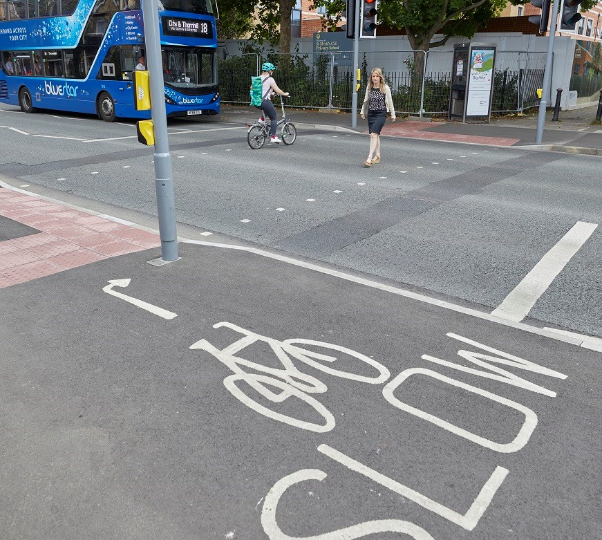 Traffic light crossing with a bike lane, cyclist, pedestrian and waiting bus