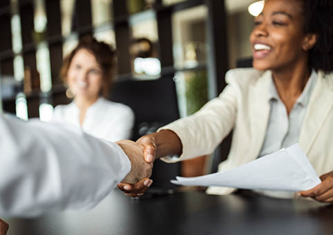 People shaking hands over a desk