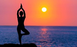 Woman doing yoga during sunset