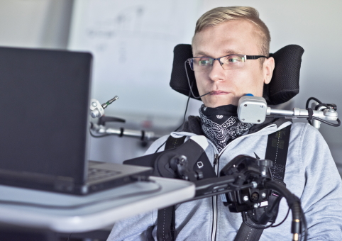 Disabled man with specialist equipment to operate laptop