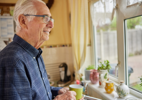 Elderly man smiling and looking out of window