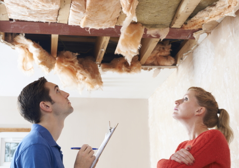 Woman and man with clipboard looking at damaged roof