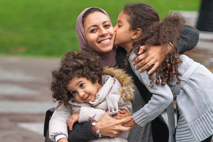A woman and two children embracing A woman and two children embracing