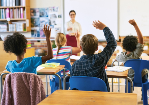 Children holding the hands up in class