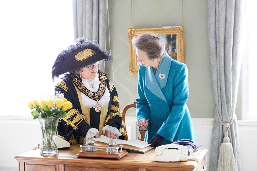 Lord Mayor Jacqui Rayment and The Princess Royal signing at a desk