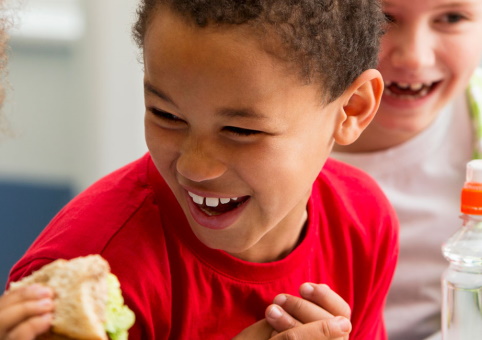 Two children laughing while holding food
